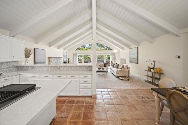 kitchen with white cabinets, decorative backsplash, and vaulted ceiling with beams