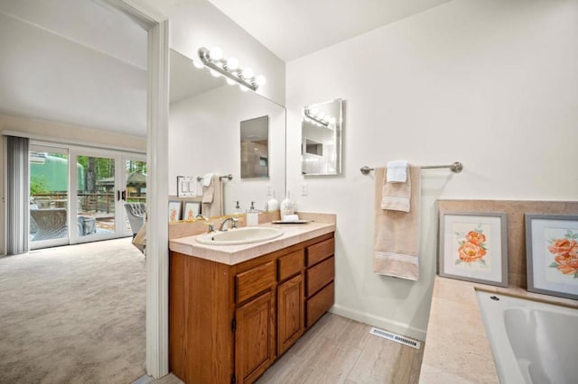 bathroom with hardwood / wood-style floors, vanity, and a tub to relax in