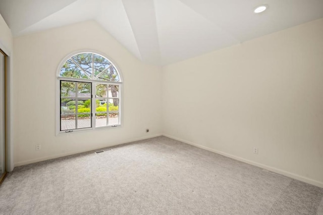 carpeted spare room with vaulted ceiling