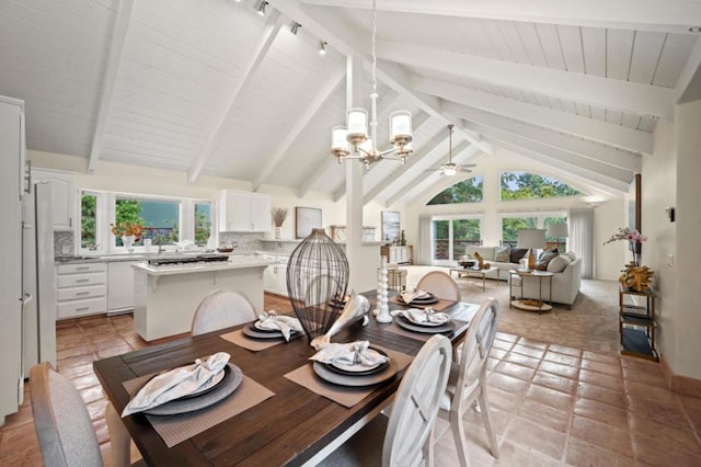 dining space with beamed ceiling, ceiling fan with notable chandelier, and high vaulted ceiling