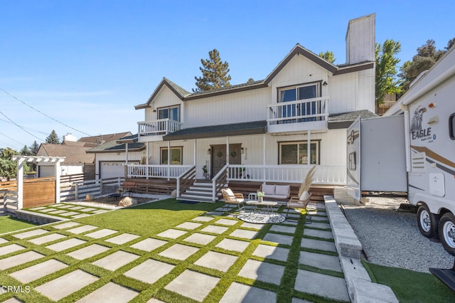 rear view of property featuring a porch, a patio, a balcony, a yard, and a garage