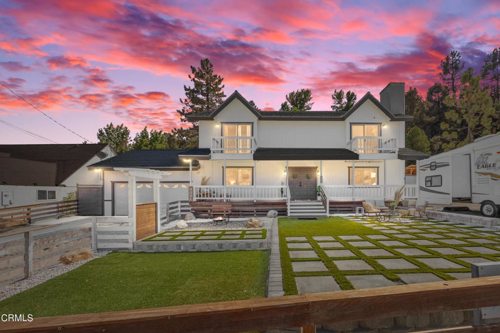 view of front of property with a pergola, a balcony, a lawn, and a patio