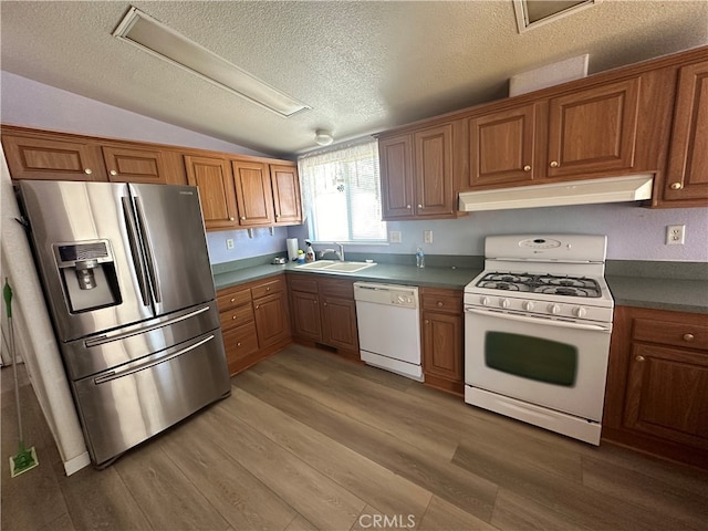 kitchen with lofted ceiling, wood-type flooring, white appliances, sink, and a textured ceiling