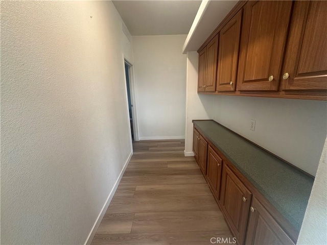 corridor with baseboards and light wood-style floors