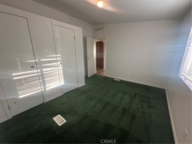 unfurnished bedroom with visible vents, arched walkways, and dark carpet