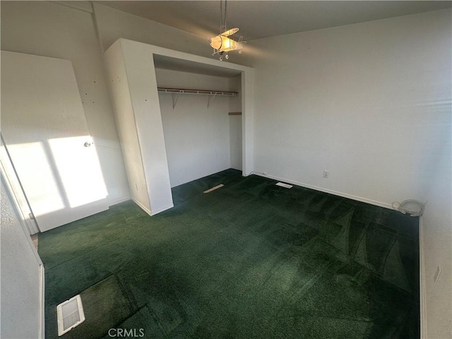 unfurnished bedroom with a closet, dark carpet, and visible vents