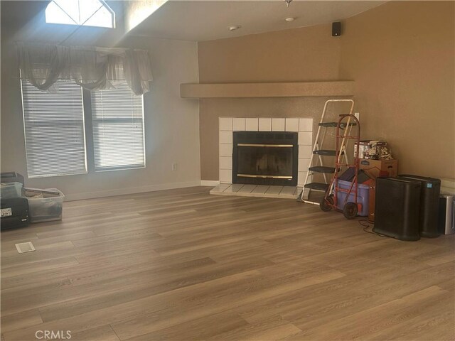 living room featuring a tiled fireplace, wood finished floors, and baseboards