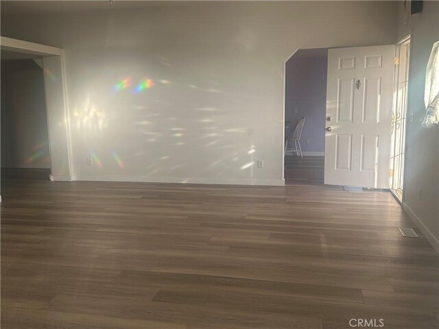 spare room featuring dark wood-style flooring and baseboards