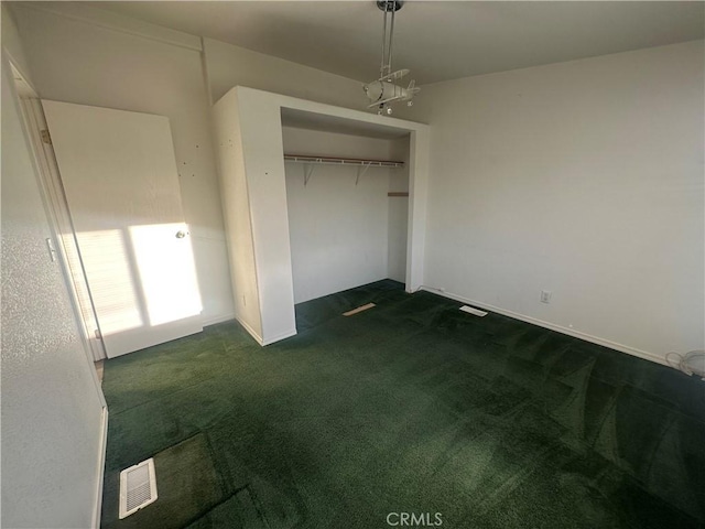 unfurnished bedroom featuring visible vents, dark colored carpet, and a closet