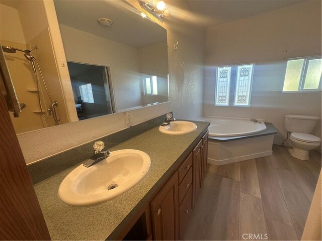 full bathroom with wood finished floors, a sink, toilet, and a bath