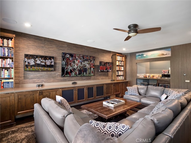 living room featuring built in shelves, dark wood-type flooring, and ceiling fan