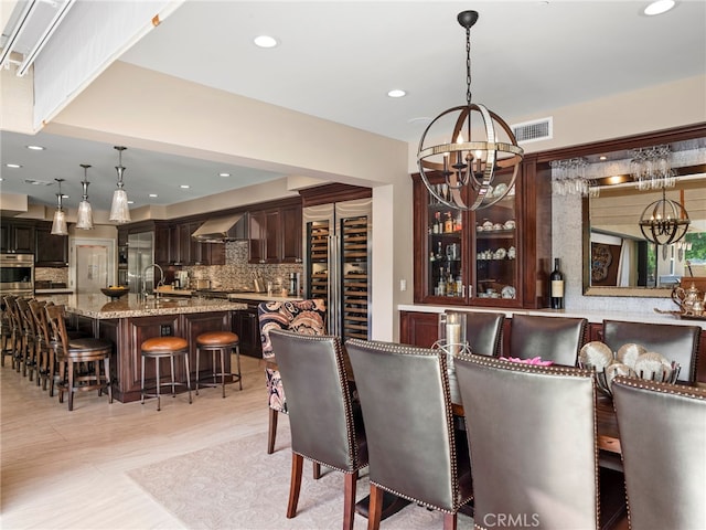 dining room with a notable chandelier, beverage cooler, light hardwood / wood-style floors, and sink