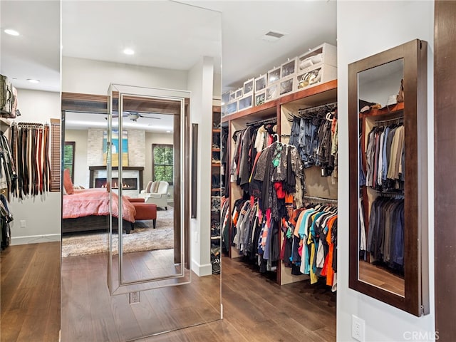 spacious closet with ceiling fan, dark hardwood / wood-style flooring, and a large fireplace