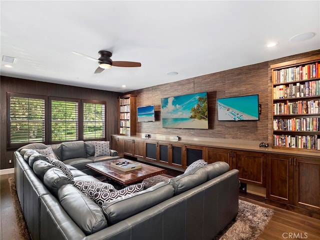 living room with wood walls, ceiling fan, and dark hardwood / wood-style flooring