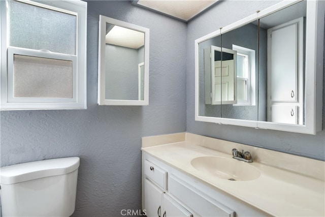 bathroom with plenty of natural light, vanity, and toilet