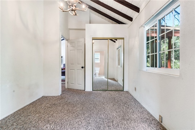 carpeted empty room with a notable chandelier, beam ceiling, and high vaulted ceiling