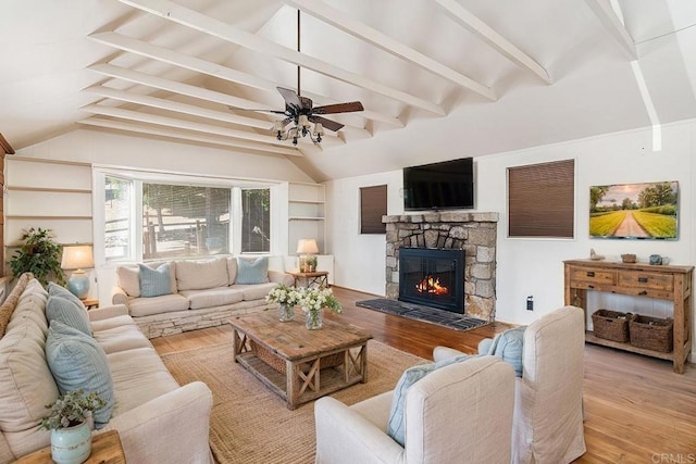 living room featuring light wood-type flooring, a fireplace, lofted ceiling with beams, and ceiling fan