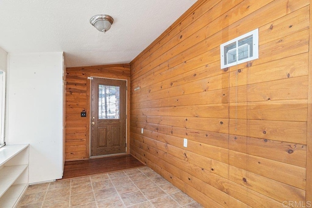 entrance foyer with wooden walls, vaulted ceiling, and light hardwood / wood-style floors