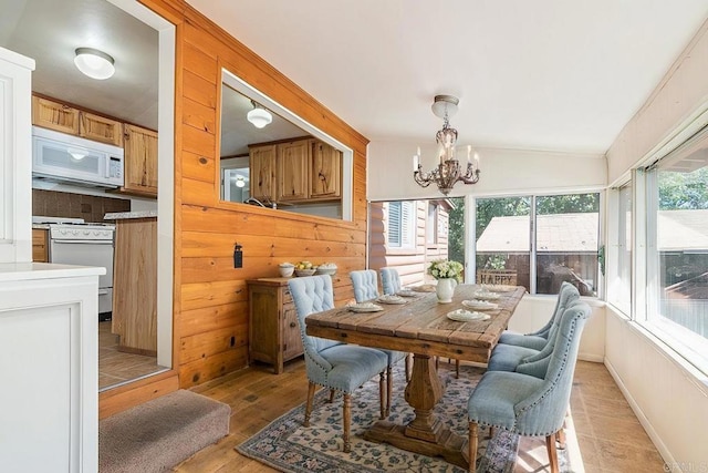 dining room with light wood-type flooring, lofted ceiling, wood walls, and a chandelier