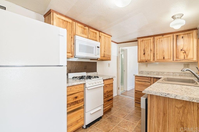 kitchen featuring a textured ceiling, light brown cabinetry, white appliances, and sink