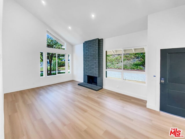 unfurnished living room featuring a fireplace, light hardwood / wood-style floors, and high vaulted ceiling