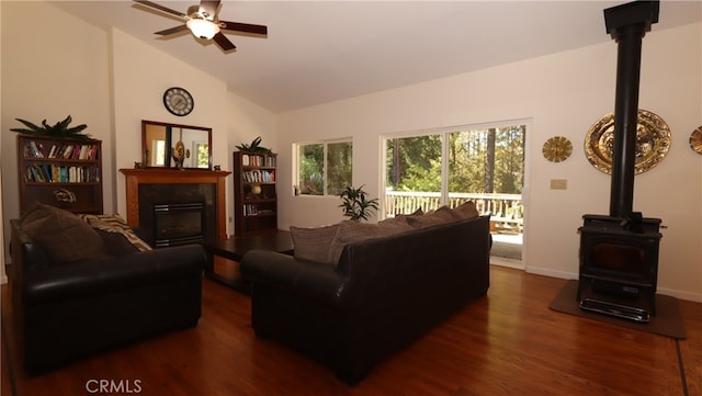 living room with ceiling fan, dark hardwood / wood-style flooring, a wood stove, and high vaulted ceiling