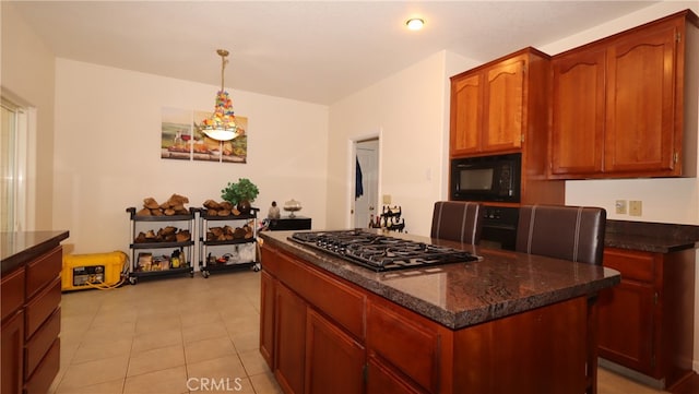 kitchen with pendant lighting, light tile patterned floors, stainless steel gas cooktop, a center island, and dark stone countertops