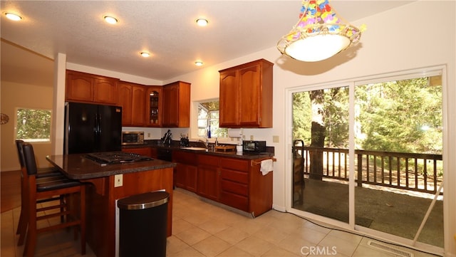 kitchen featuring stainless steel appliances, a textured ceiling, a kitchen bar, a center island, and sink