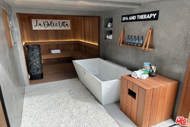 bathroom featuring hardwood / wood-style flooring, beamed ceiling, and a washtub