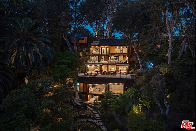 back house at night featuring a balcony