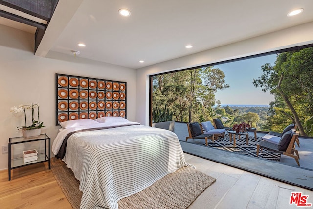 bedroom featuring light hardwood / wood-style floors, beam ceiling, and access to exterior