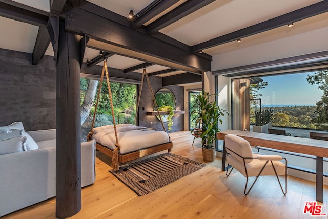 bedroom with light hardwood / wood-style flooring and beam ceiling