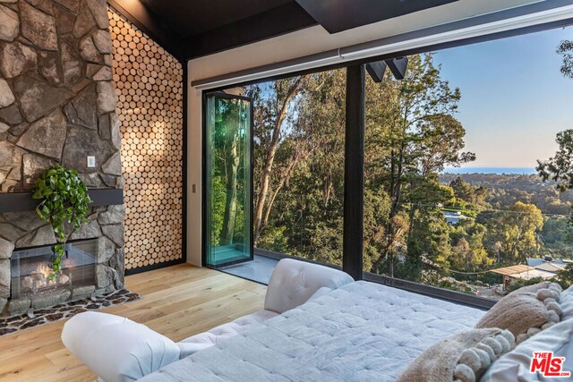 unfurnished bedroom with an outdoor stone fireplace and wood-type flooring