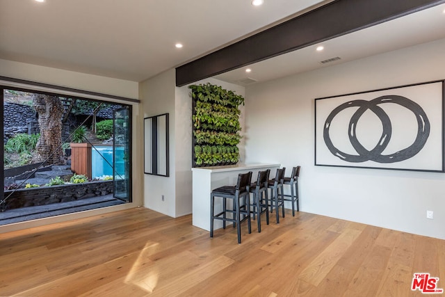 bar featuring beam ceiling and light wood-type flooring