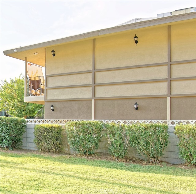 view of side of home featuring a balcony and a yard