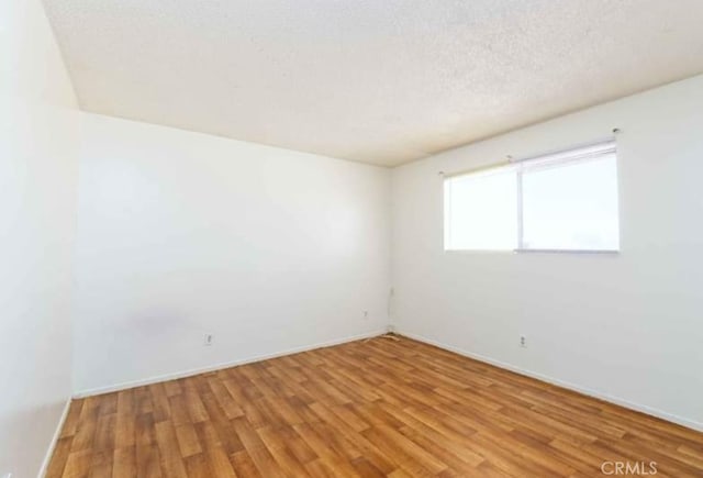 unfurnished room featuring a textured ceiling and light wood-type flooring