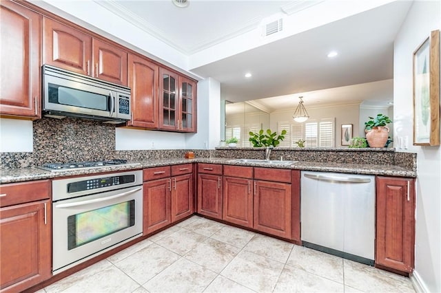 kitchen with dark stone countertops, stainless steel appliances, crown molding, and sink