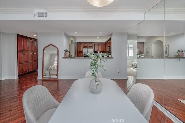 dining space with ornamental molding and dark wood-type flooring