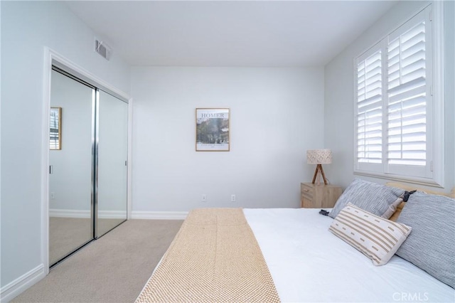 bedroom with multiple windows, light colored carpet, and a closet