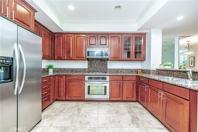 kitchen with dark stone counters, stainless steel appliances, ornamental molding, and sink