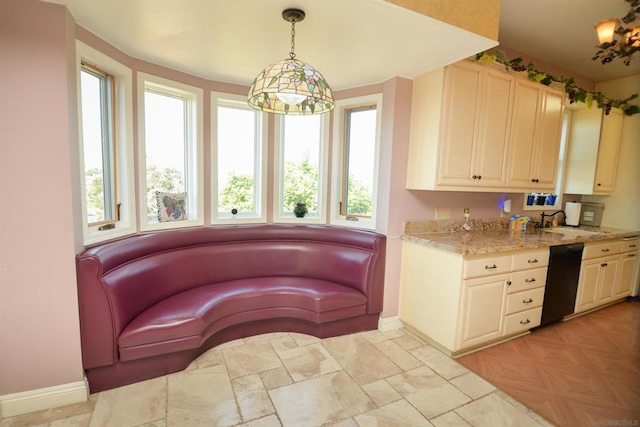 interior space featuring light stone countertops, black dishwasher, sink, and pendant lighting