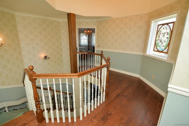 stairway featuring hardwood / wood-style flooring, crown molding, a chandelier, and a wealth of natural light