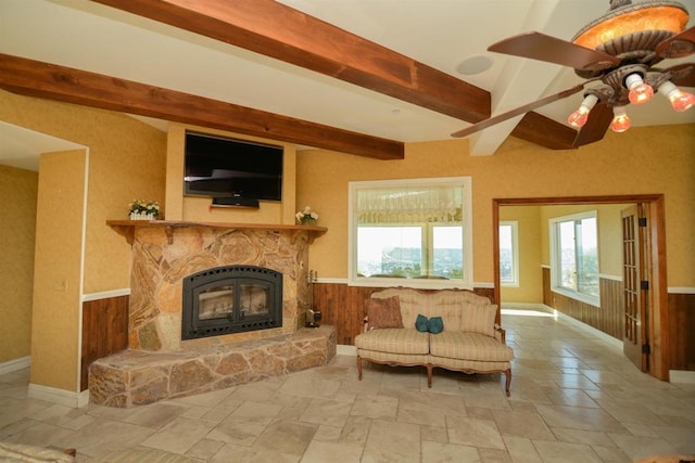 living room with a fireplace, wood walls, ceiling fan, and beamed ceiling