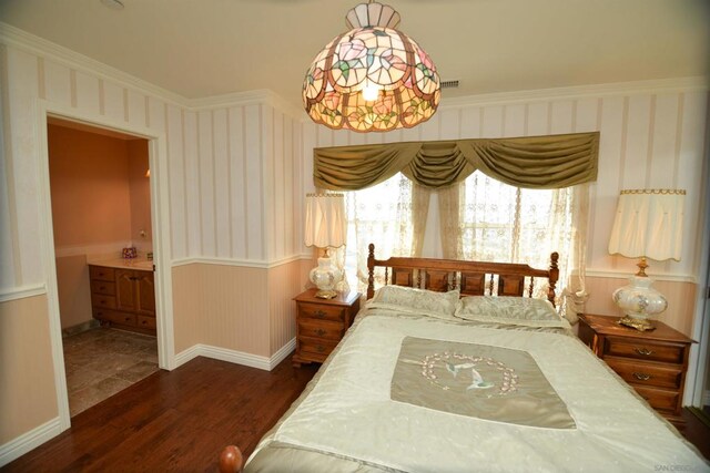 bedroom with crown molding, ensuite bath, and dark hardwood / wood-style flooring