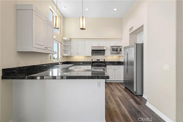 kitchen featuring kitchen peninsula, sink, appliances with stainless steel finishes, decorative light fixtures, and white cabinetry