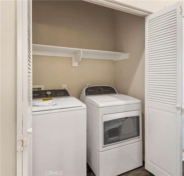 laundry room with washing machine and clothes dryer and dark wood-type flooring