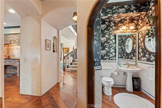 bathroom featuring toilet, a fireplace, wood-type flooring, and sink