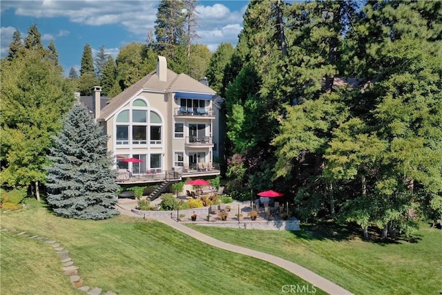 back of house featuring a lawn, a balcony, and a patio