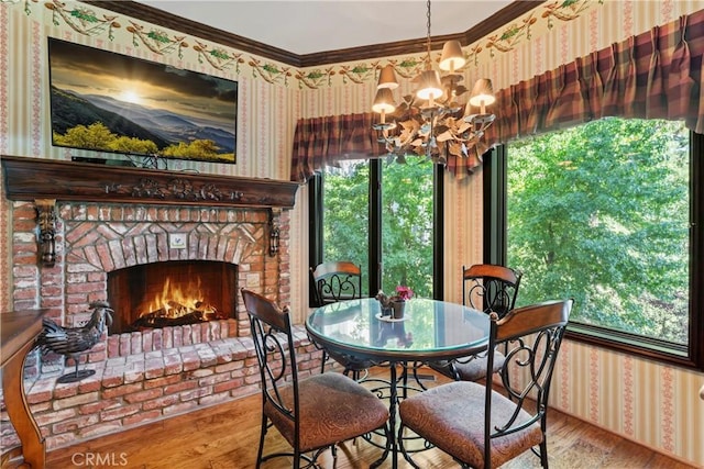 dining area with crown molding, a fireplace, an inviting chandelier, and hardwood / wood-style flooring