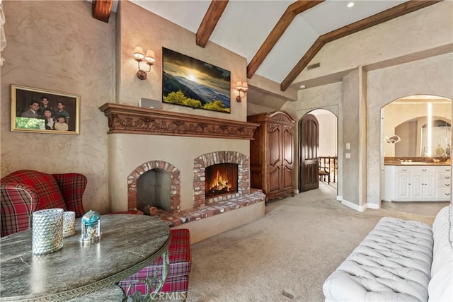 carpeted living room featuring beam ceiling, a fireplace, and high vaulted ceiling